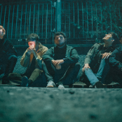 Members of the band 'Vida' sitting on a kerb